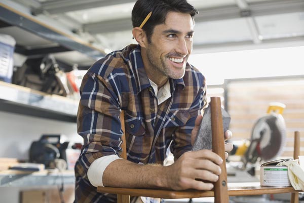 A man sanding a piece of wood in a workshop