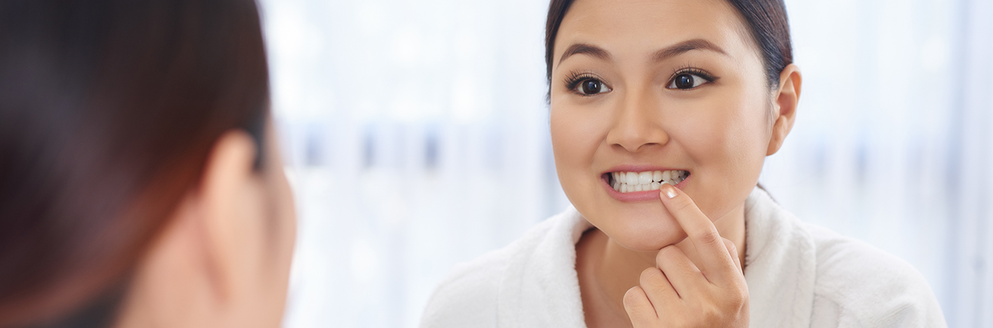 A woman looking at her teeth in a mirror