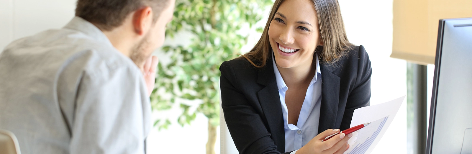 A broker talking with a client at a desk