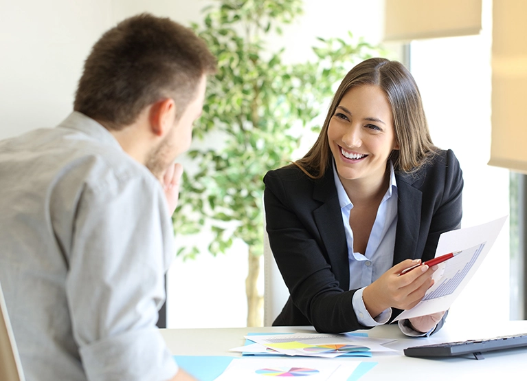 A broker talking with a client at a desk