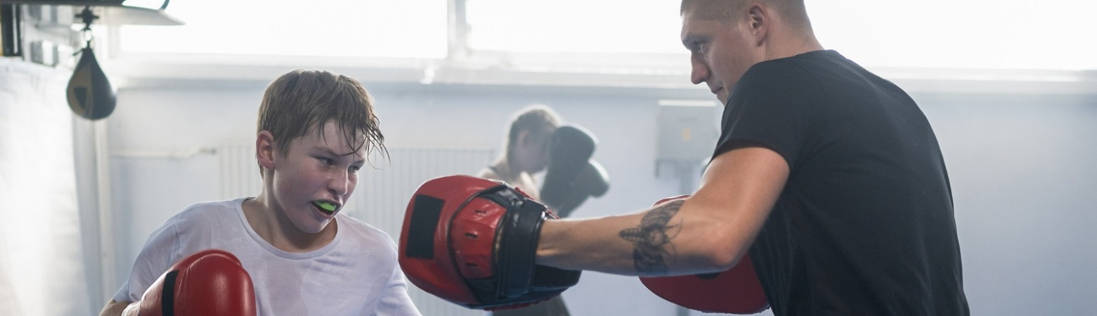 Young male boxer with a mouth guard sparing with his adult coach