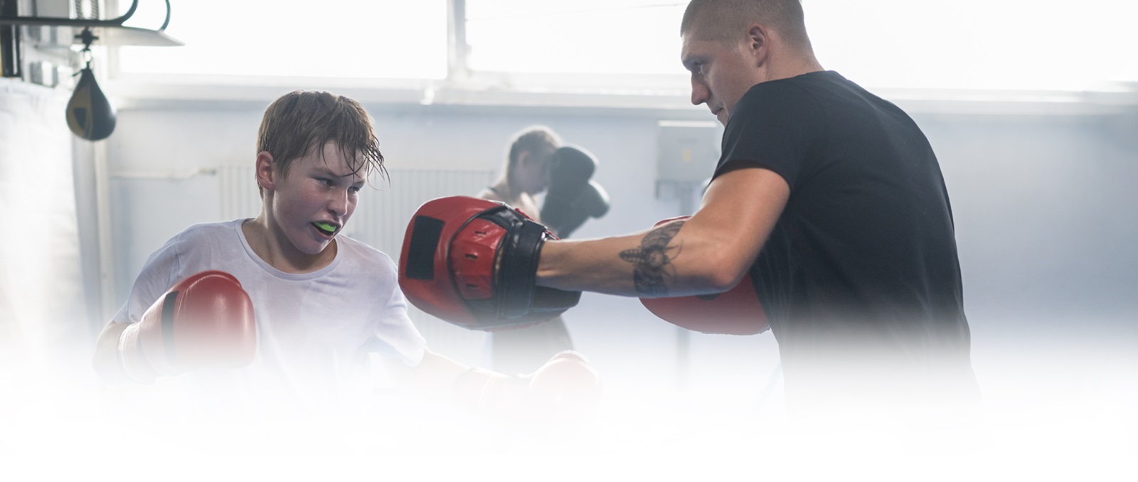 Young male boxer with a mouth guard sparing with his adult coach