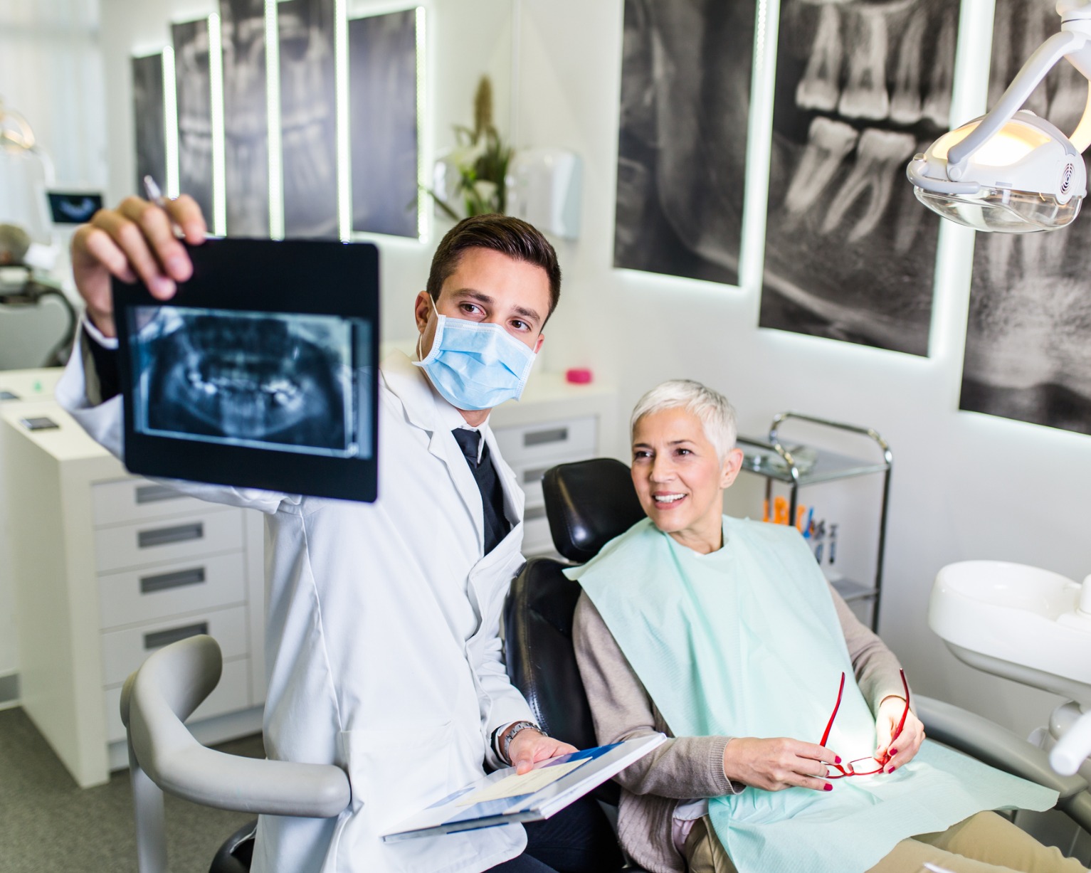 A dentist and patient looking at teeth x-rays