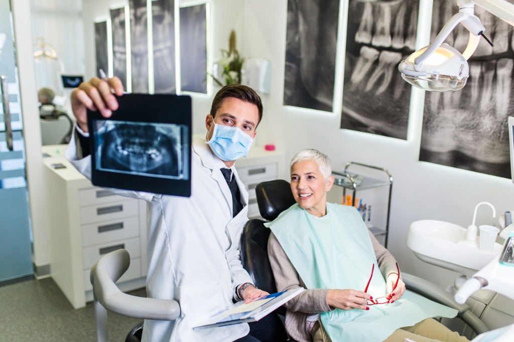 A dentist and patient looking at teeth x-rays