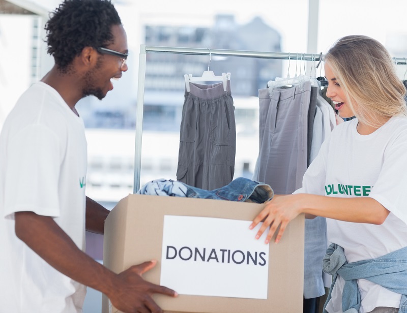 Cheerful volunteers looking at a donation box