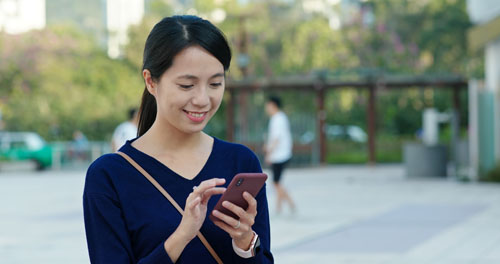 Young Woman work on smart phone and sit on the bench