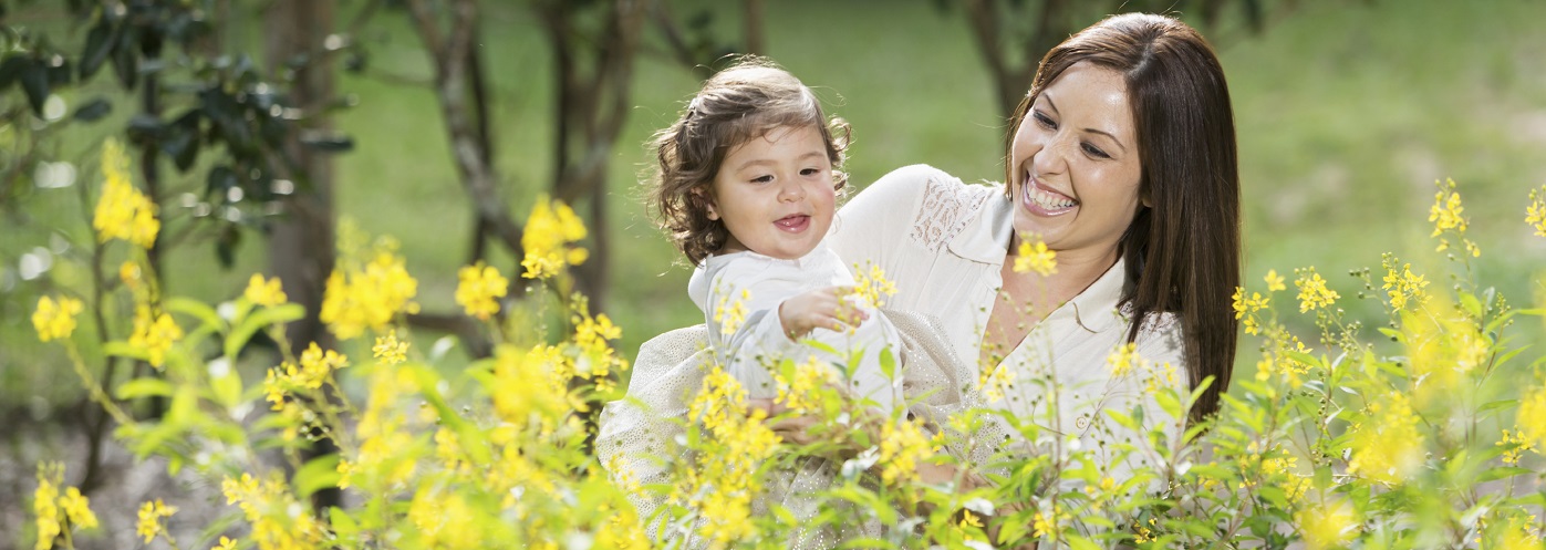 Hispanic mother (30s) with little girl (17 months) reaching for flowers.